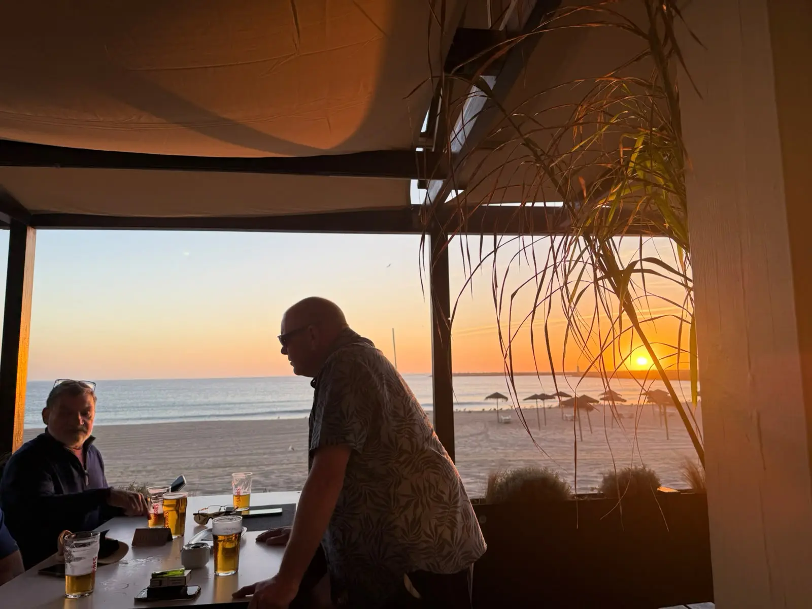Golfers sharing drinks beside a beach at sunset