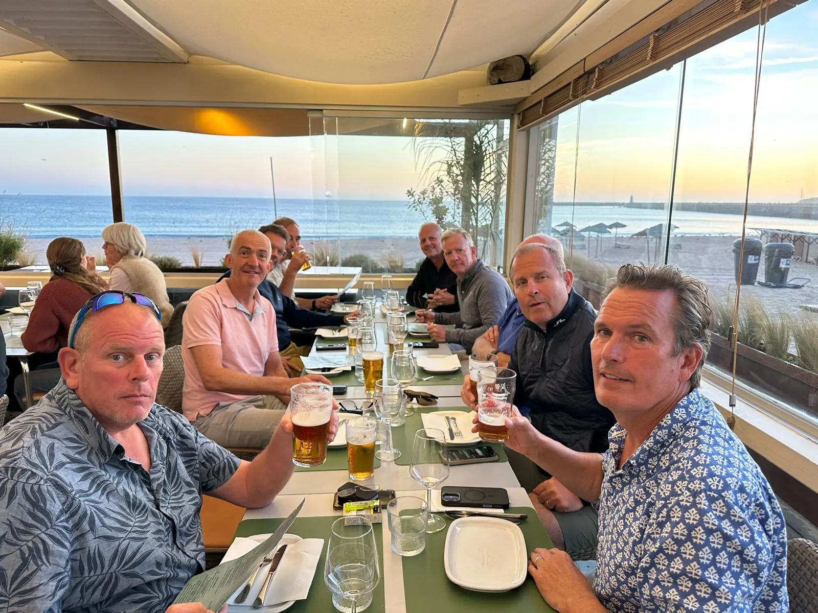 The group seated around a restaurant table overlooking the sea